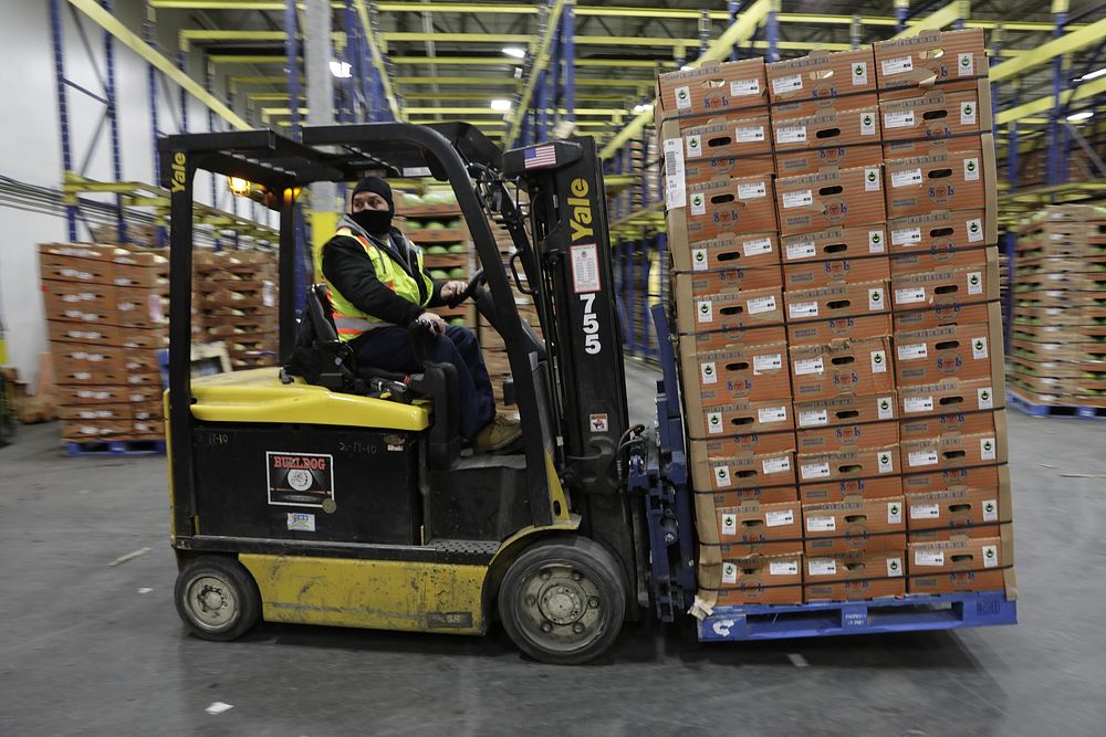 Photograph of a forklift being used to move stacks of cardboard boxes on a pallet