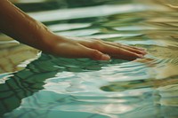 Hand touching water surface pool outdoors nature.