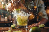 Barman hand squeezing fresh juice from lime in the glass making the Caipirinha cocktail on the bar accessories accessory beverage.