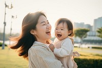 Happy Asian mother plays with daughter laughing happy baby.
