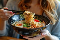 Cropped hand of asian woman eating a bowl of freshly served traditional Japanese ramen with chopsticks cutlery person human.