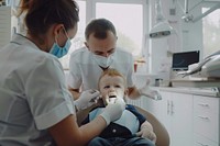 Checking teeth of child sitting on dentist chair electronics clothing hardware.