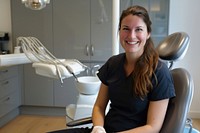 Woman smile sitting on dentist chair and dentist standing on side furniture clothing apparel.