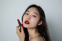 Asian holding red lipstick with confident pose cosmetics person makeup.