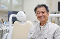 Asian man smile sitting on dentist chair furniture clothing apparel.