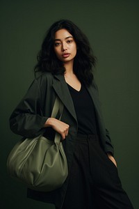 Woman wearing dark green jacket and gray jeans photo bag accessories.