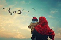 Refugee woman holding a child look at birds flying away photo sky photography.