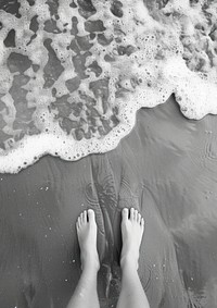 Feet standing on sand beach sea shoreline.