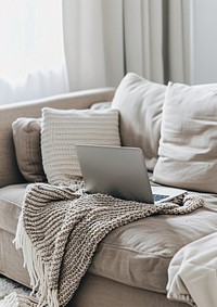 An open laptop on the sofa blanket couch electronics.