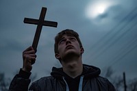 Young man holding cross photo photography outdoors.