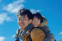 Young asian father carrying son on back outdoors photo photography.
