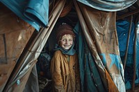 Ukraine refugee stands inside an old tent clothing apparel person.