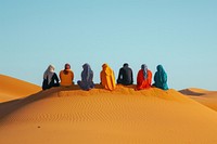 Six middle east friends sitting on top of the sand dunes outdoors desert nature.