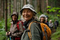 Smiling senior woman hiking with friends backpacking recreation adventure.