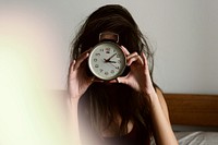 Girl holding a clock in front of her face