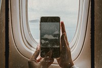 Woman capturing clouds from the plane window with her phone