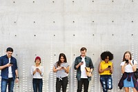 Group of young adults outdoors using smartphones together and chilling