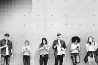 Group of young adults outdoors using smartphones together and chilling