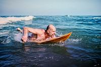 Senior man on a surfboard in ocean