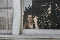 Girl looking out the window of her LA home during the covid-19 pandemic