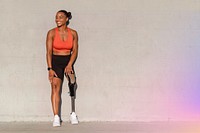 Paralympic athlete with prosthetic leg smiling by the wall