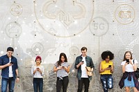 Group of young adults outdoors using smartphones together and chilling