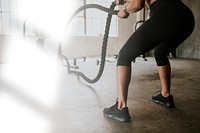 Sportive woman doing a battle rope in a gym