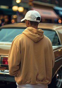 A man wearing an oversized hoodie and white cap sweatshirt clothing knitwear.