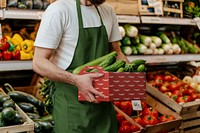 Grocery store worker carrying vegetable paper box