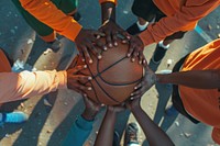 A black people holding hands in a huddle over basketball on hardcourt sports person human.