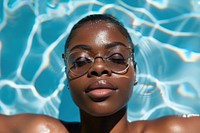 Black women lying down in the sun wearing glasses on the pool accessories photography recreation.