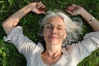 Delighted middle aged female lying on grass photo photography accessories.