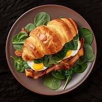 A classic croissant sandwich with bacon brunch plate food.