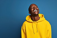 A Middle age black people waring yellow sweater laughing sweatshirt clothing.