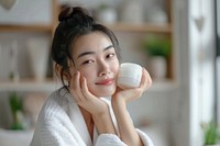 Asian Woman Applying Face Cream in her Home woman face dimples.
