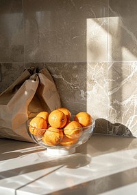 Kitchen counter from the front view with a glass bowl full of oranges and a paper brown bag produce fruit plant.