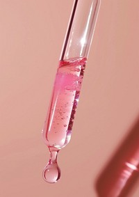Clear oil serum with pink giltter flowing out of the skincare dropper bottle shaker test tube.
