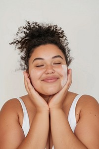 A chubby woman applying facial scrubb to both cheeks happy person female.