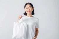 Asian woman in 60s in white tee holding a white tote bag mock up accessories accessory clothing.