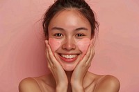 Happy asian woman in 40s apply pink facial scrubb to both cheeks skin surprised person.
