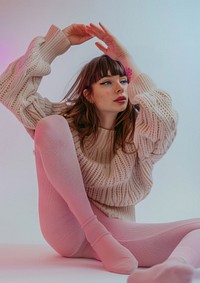 An attractive woman sitting on the floor wearing pink tights and a long-sleeved top sweater clothing knitwear.