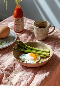 Asparagus with a poached egg in an elegant terracotta bowl food mug ketchup.