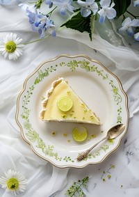 A slice of key lime pie on an elegant plate decorated with tiny dot in green script dessert spoon cheesecake.