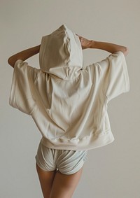 Woman put an oversized beige hoodie on pastel blue short romper shorts clothing apparel.