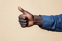 A hand of an African man with his thumb up thumbs shirt blue.