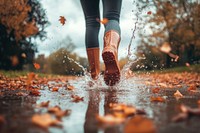 A person wearing rain boots walk in puddles on an autumn day splashing leaves woman.