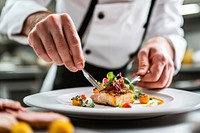 An executive chef plating up an exquisite dish on a white plate food professional presentation.