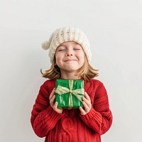 A cute caucasian 7 years old girl with blonde bob hair wearing a red Christmas sweater smiling green white.