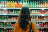 Young woman looking at bottle of juice in grocery store supermarket accessories environment.