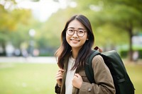 Smiling young chinese woman student wearing glasses and casual background clothing backpack.